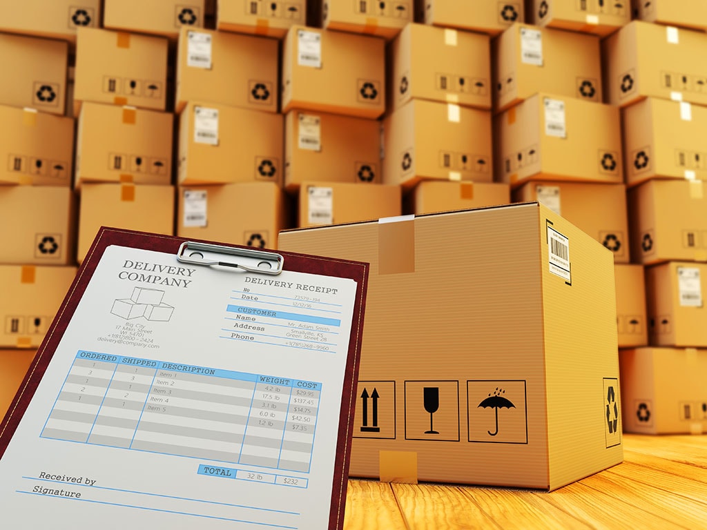 A delivery checklist beside stacked shipping cartons, illustrating the carton and document checks needed before dispatch