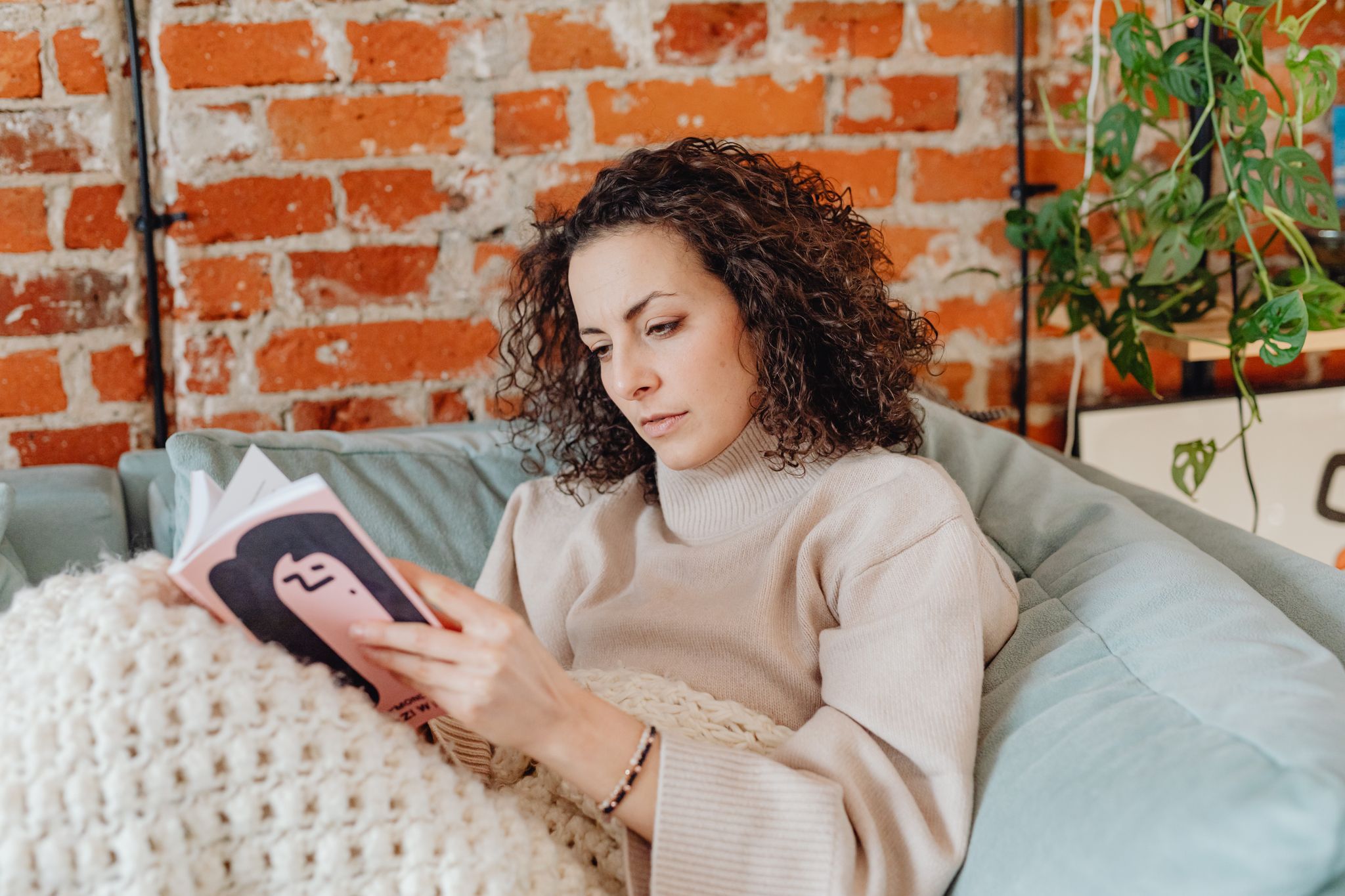 Woman wearing a soft neutral knit while relaxing at home, used as a supplied lifestyle reference for loungewear product development
