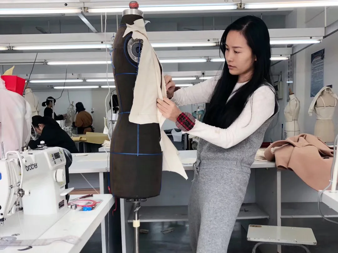 Yinshan Fashion sample-room technician draping and checking a womenswear toile on a dress form before sample approval
