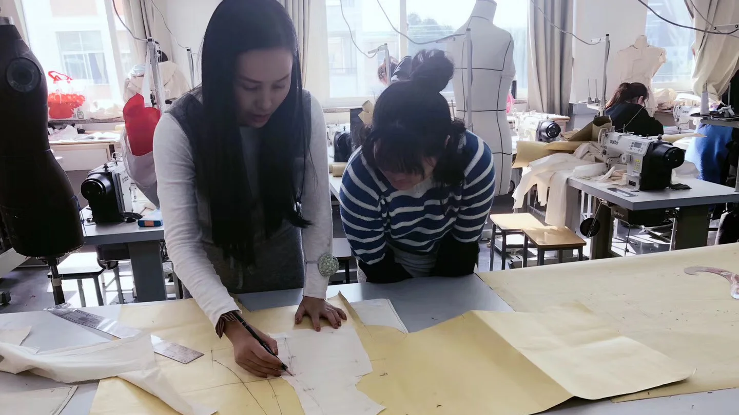 Yinshan Fashion pattern-room team reviewing womenswear pattern pieces on a worktable before sample making