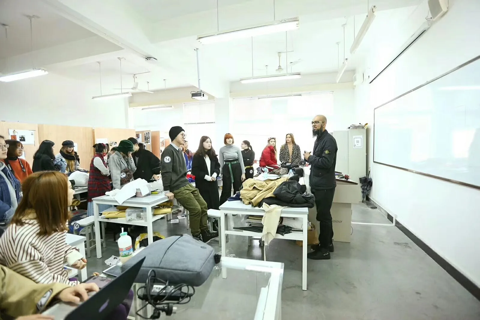 A team discussing garments and sample work in a development room, illustrating the review needed to hand over current production references