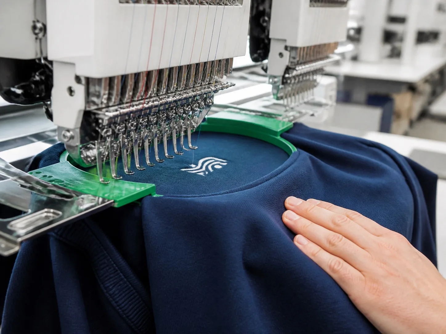 Multi-head embroidery machine stitching an emblem onto a navy fashion sweatshirt
