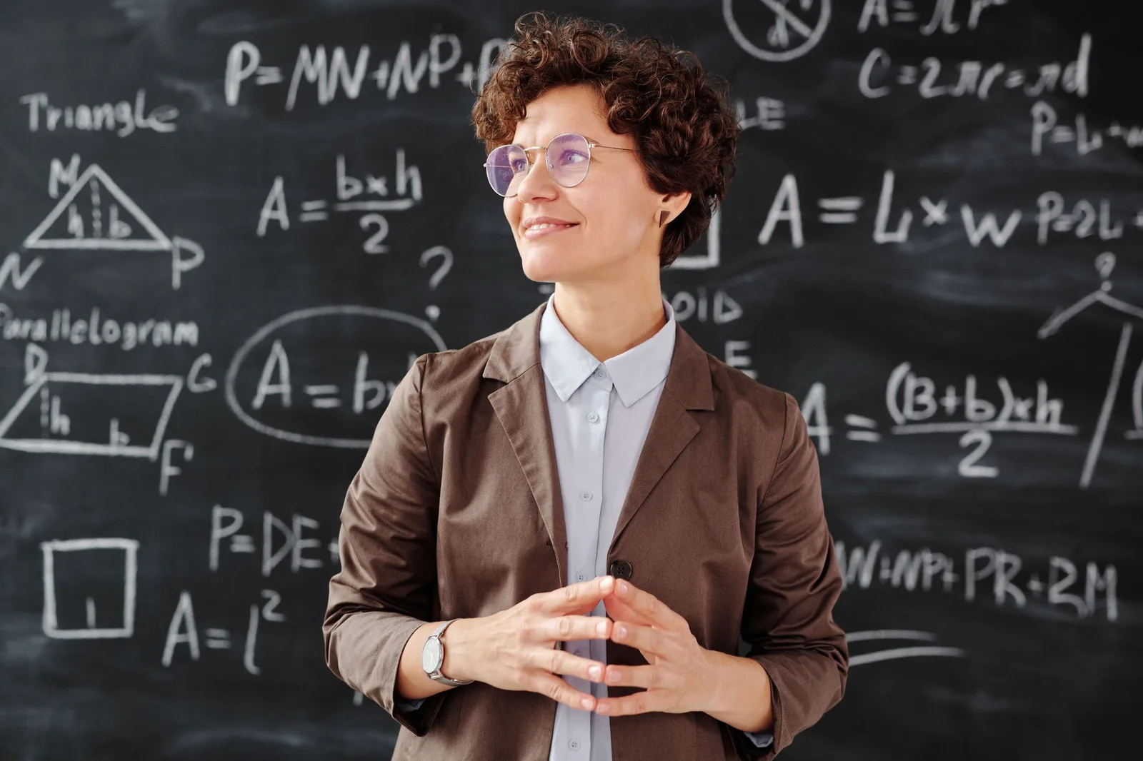 Fashion professional in a brown blazer standing before a calculation board, used as a quote-comparison reference