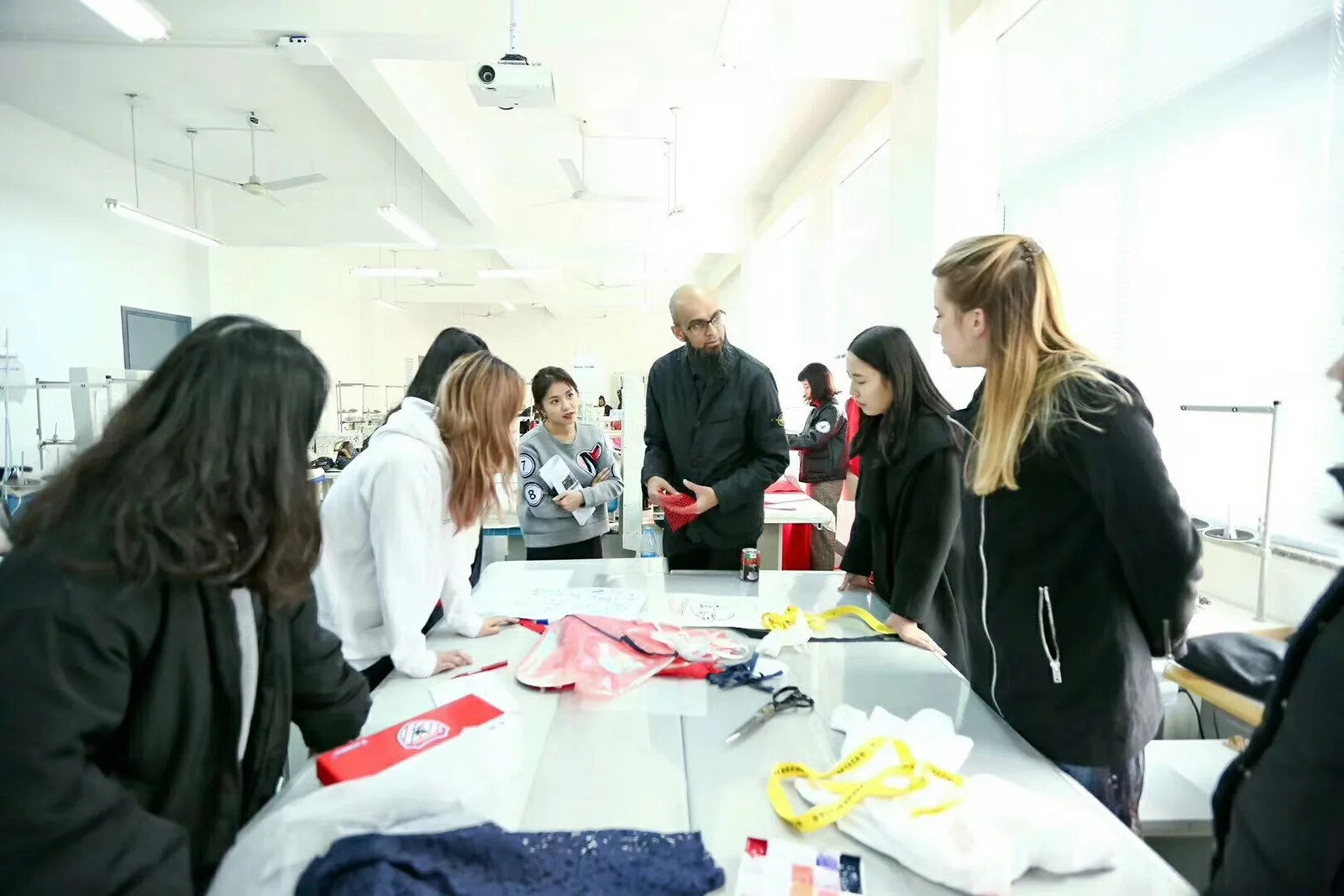 Product-development team reviewing garment samples, fabric swatches, and construction details at a worktable