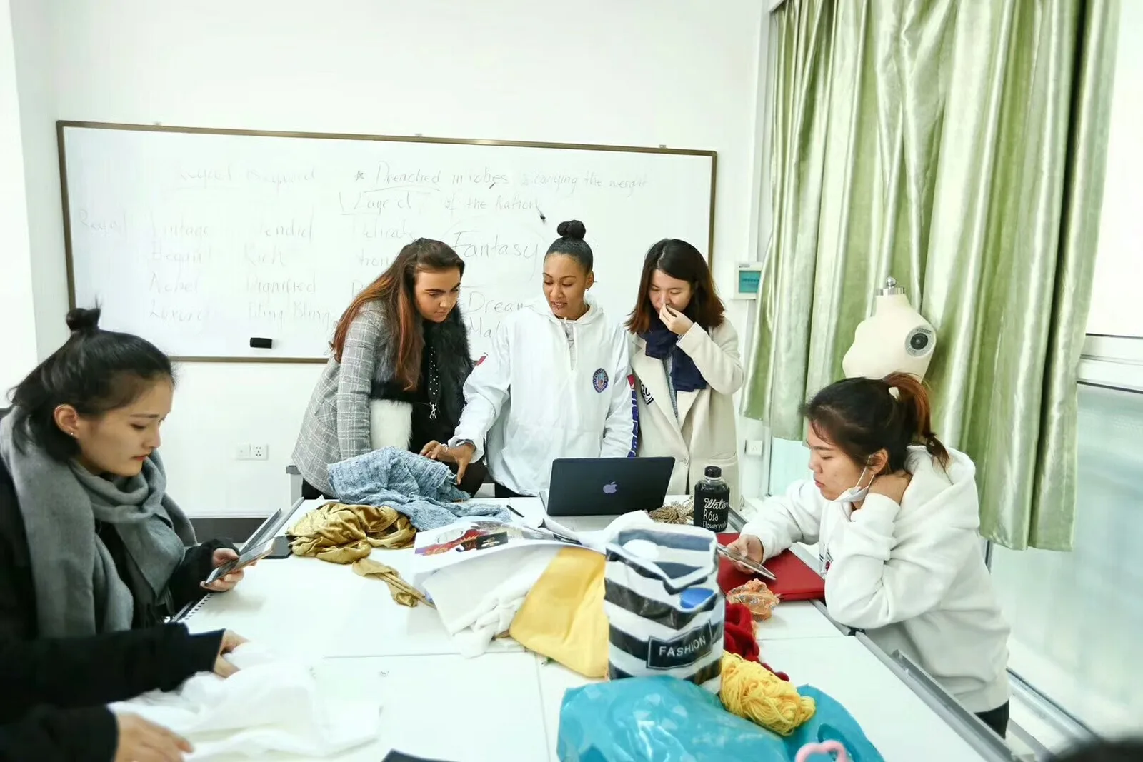Garment development team reviewing patterns, samples and fabric options around a worktable