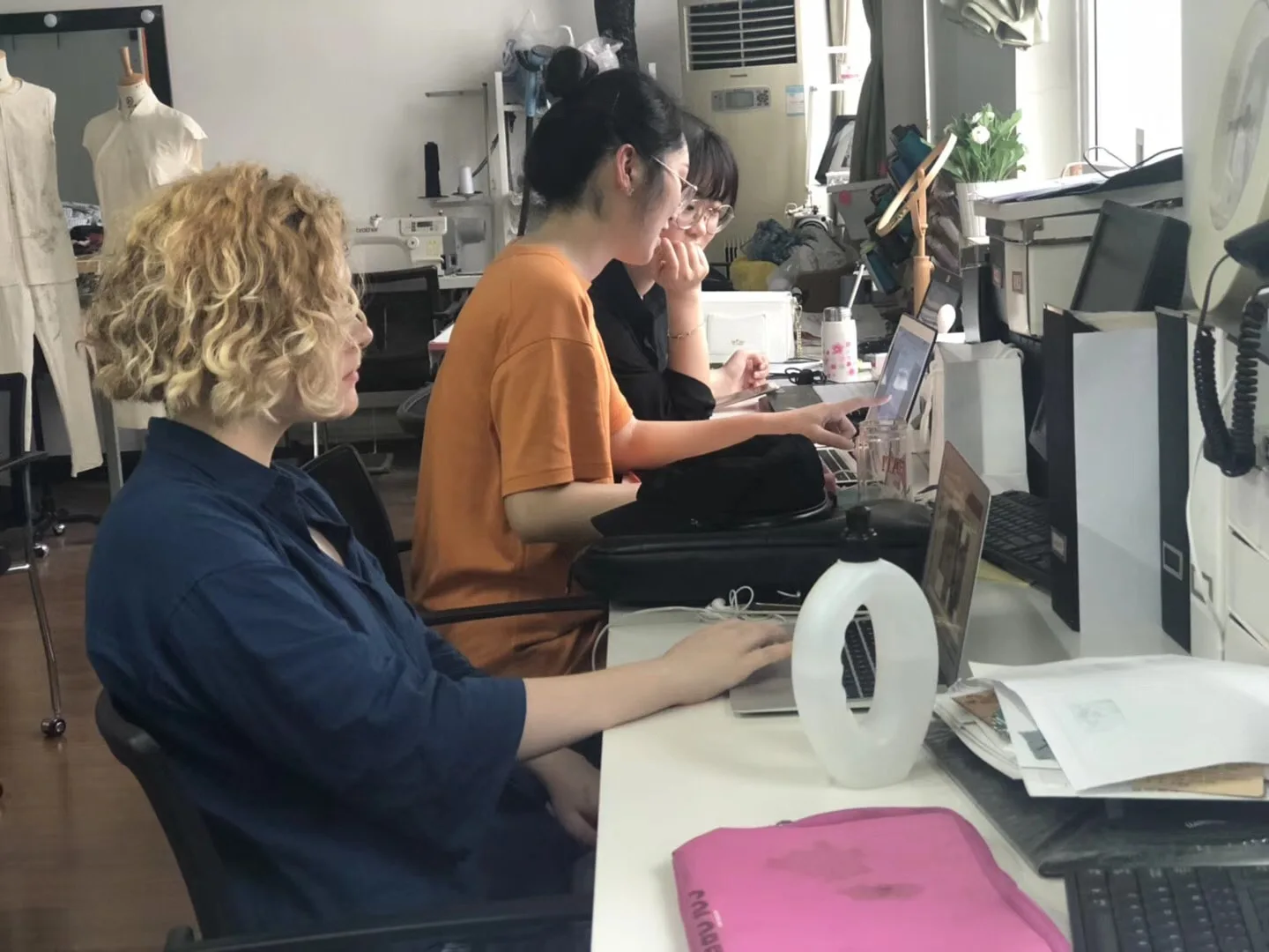 Garment sample developers working at sewing machines in a development studio