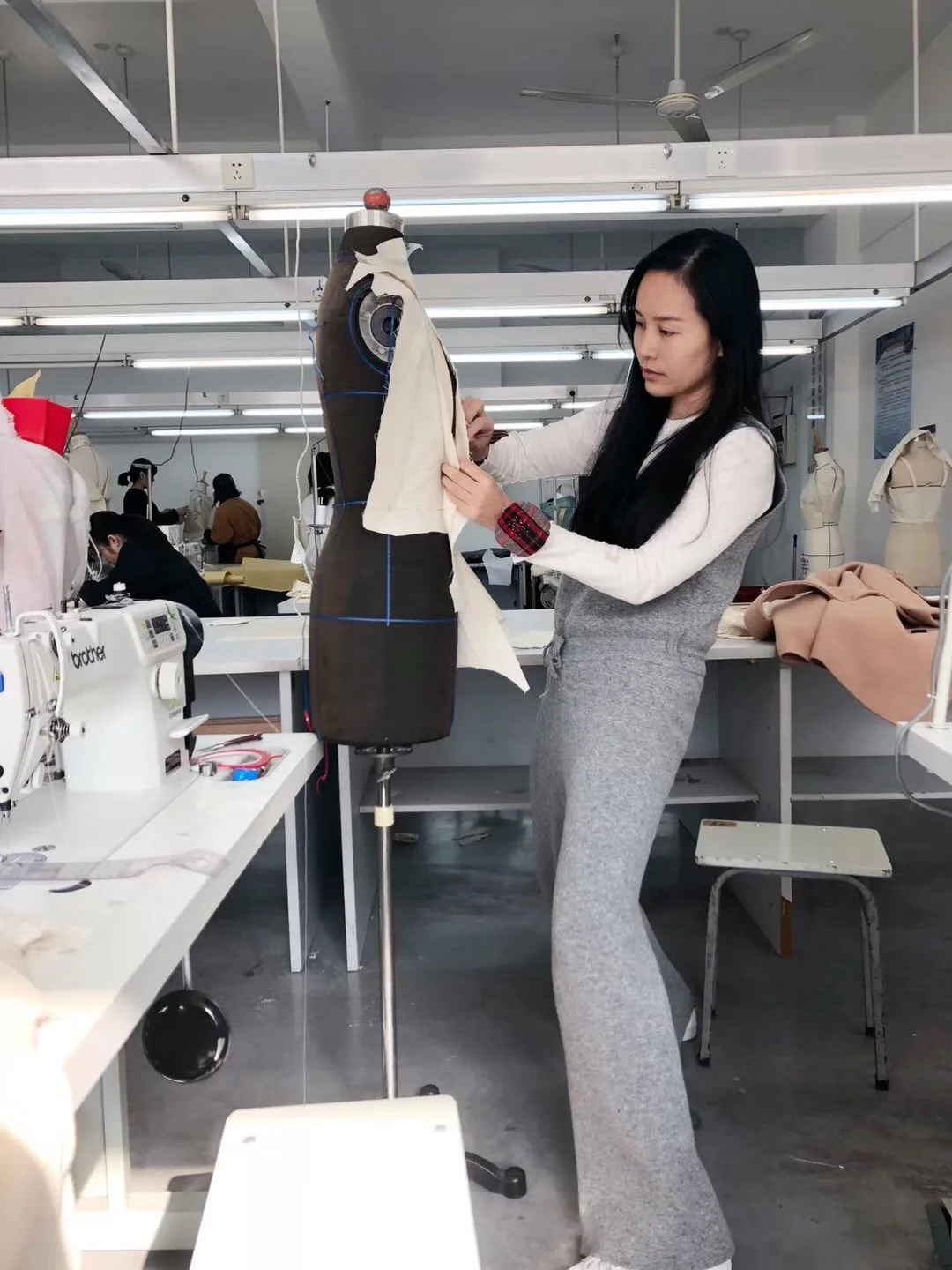 A sample technician checking garment fit on a dress form in a pattern and sample room