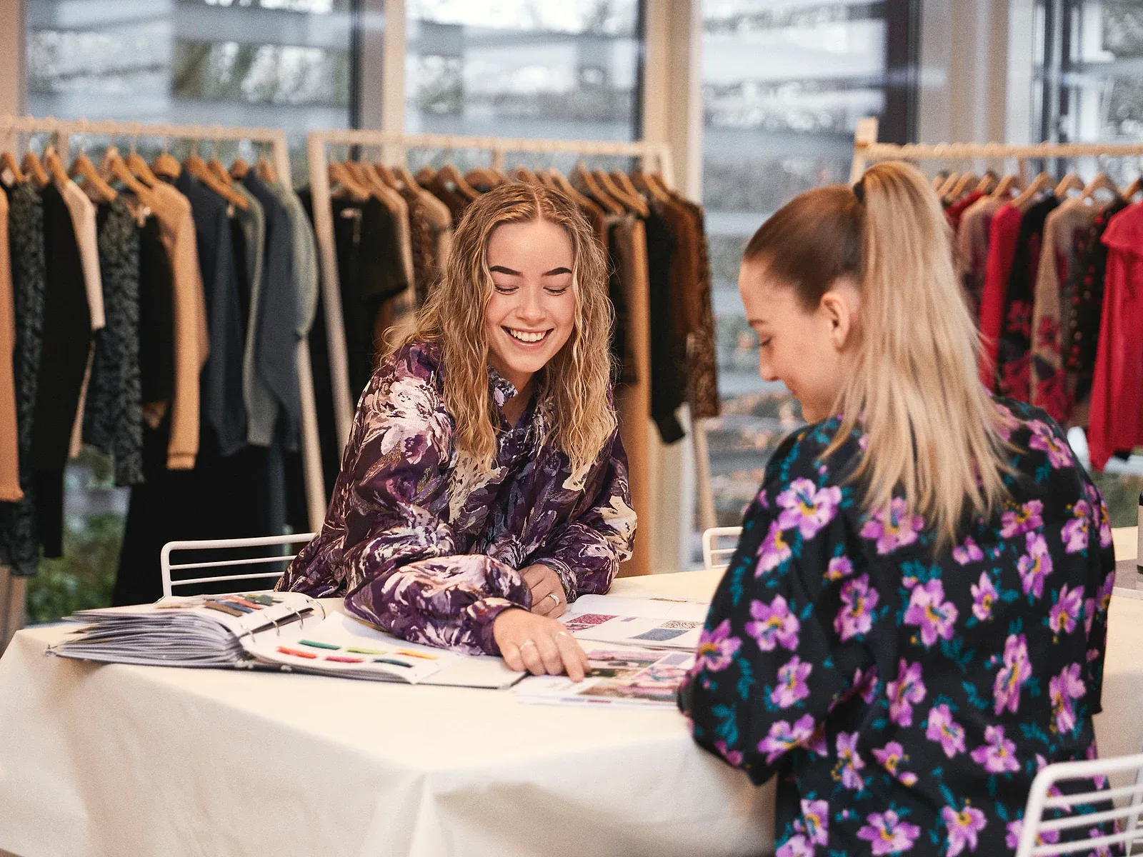 Fashion buyers reviewing apparel collections, material references, and sourcing notes together.