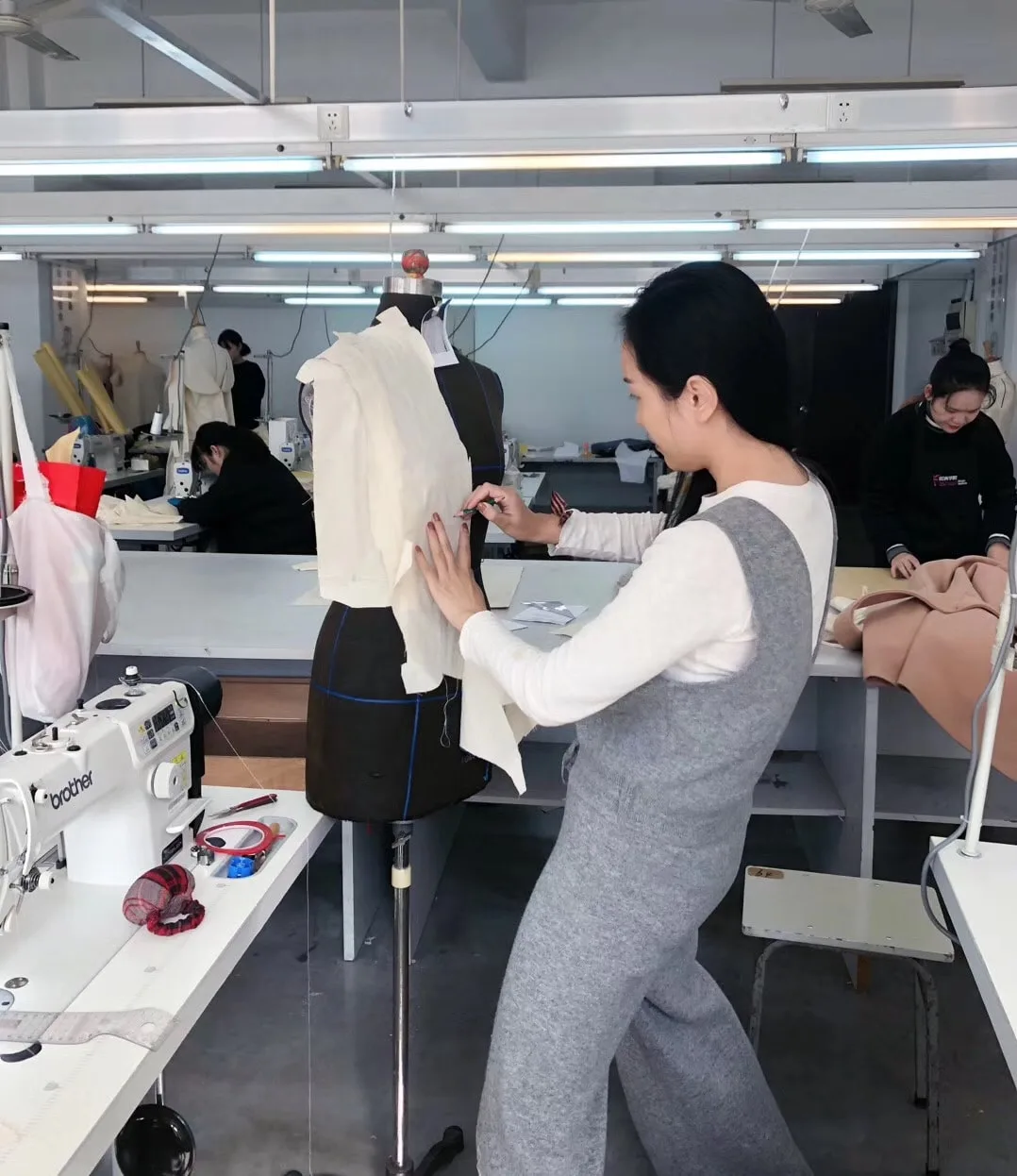 Sample developer checking a white garment on a dress form before fit approval