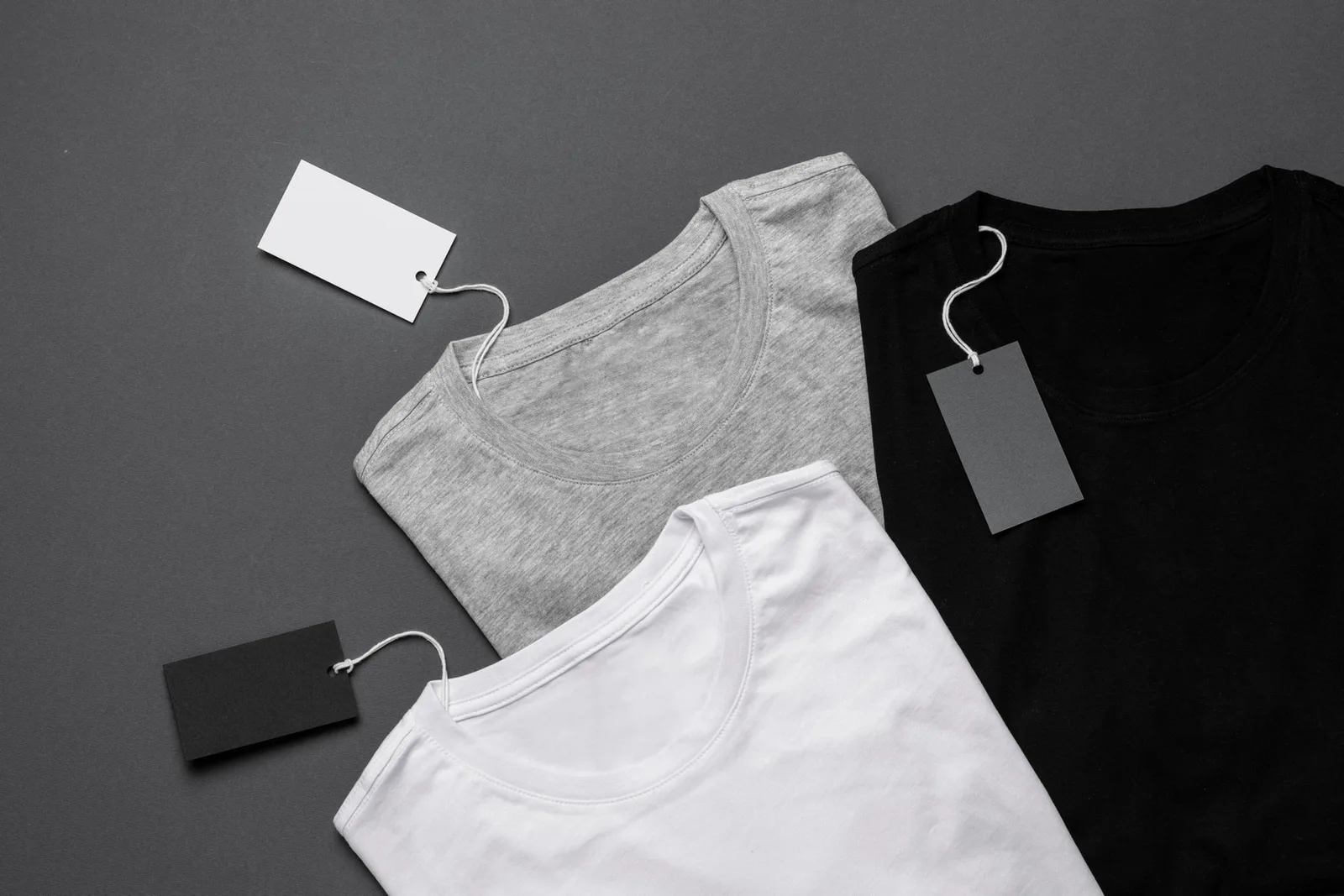 Different garment colourways with attached blank hangtags, used as a reference for product-version and label placement decisions