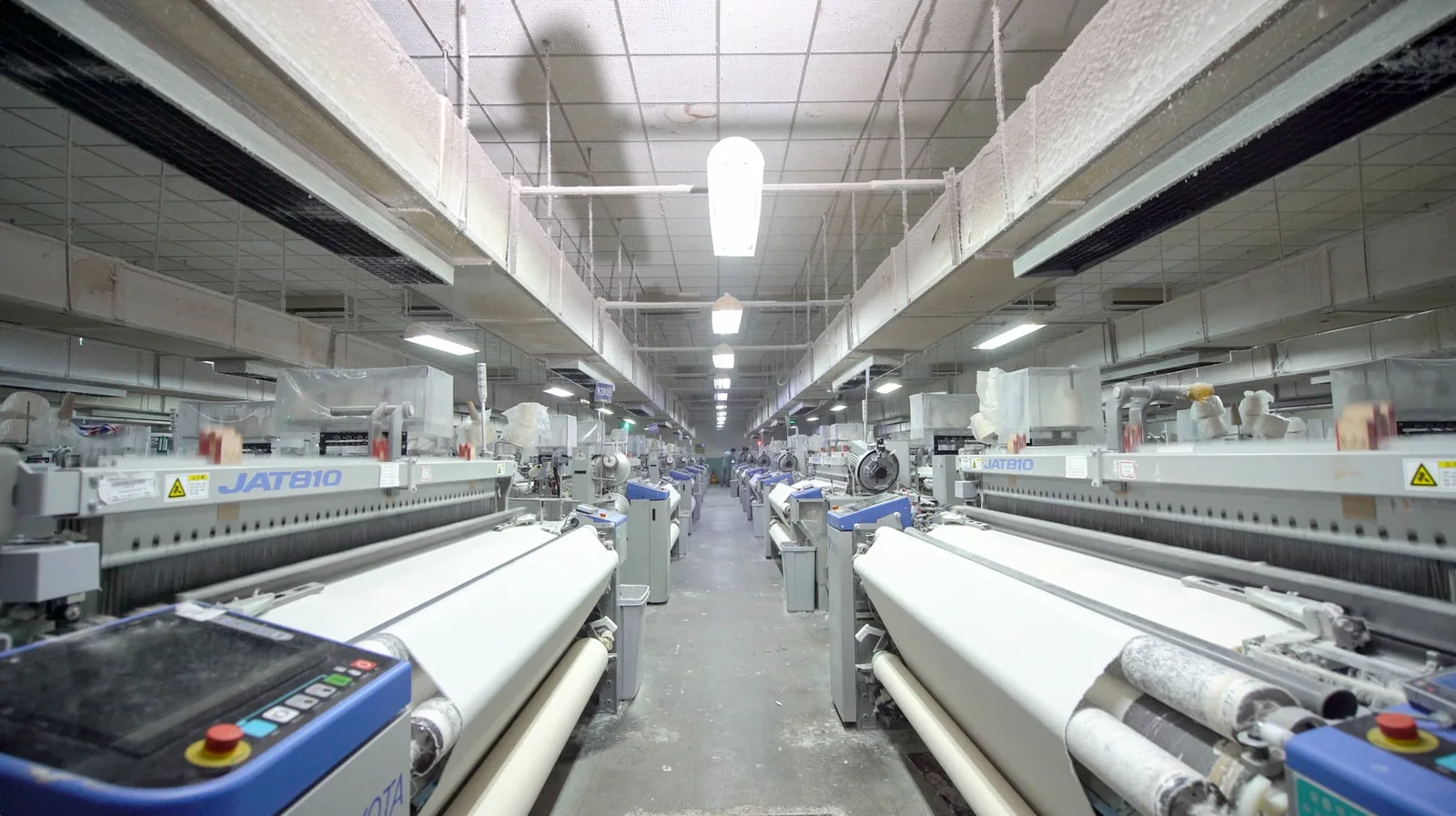 Rows of fabric-making equipment illustrating the upstream material capacity that can affect apparel production scheduling