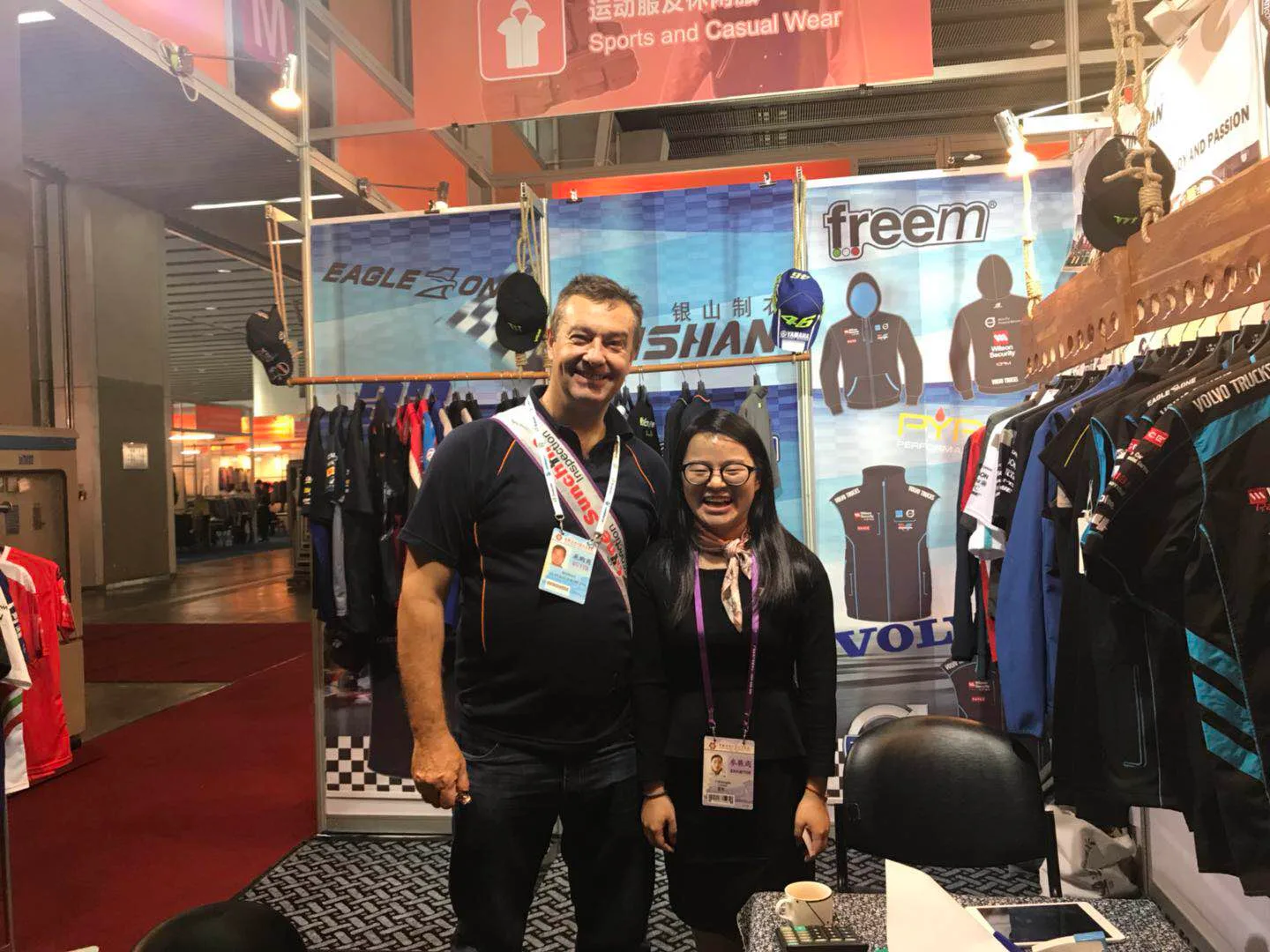 Yinshan Fashion exhibition team meeting a buyer beside apparel displays