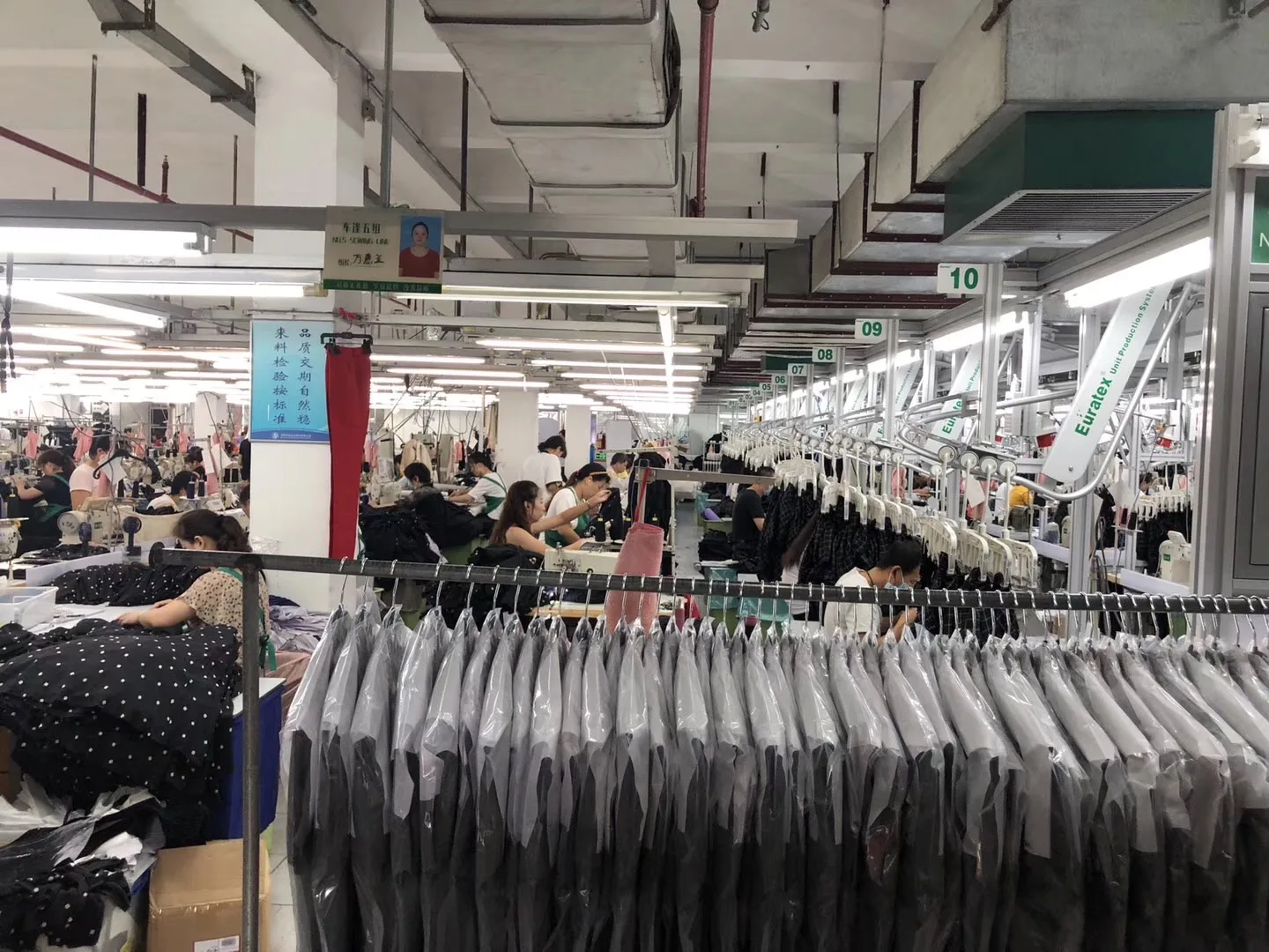 Real Yinshan Fashion production floor with operators, finished garments, and an overhead hanging-line system