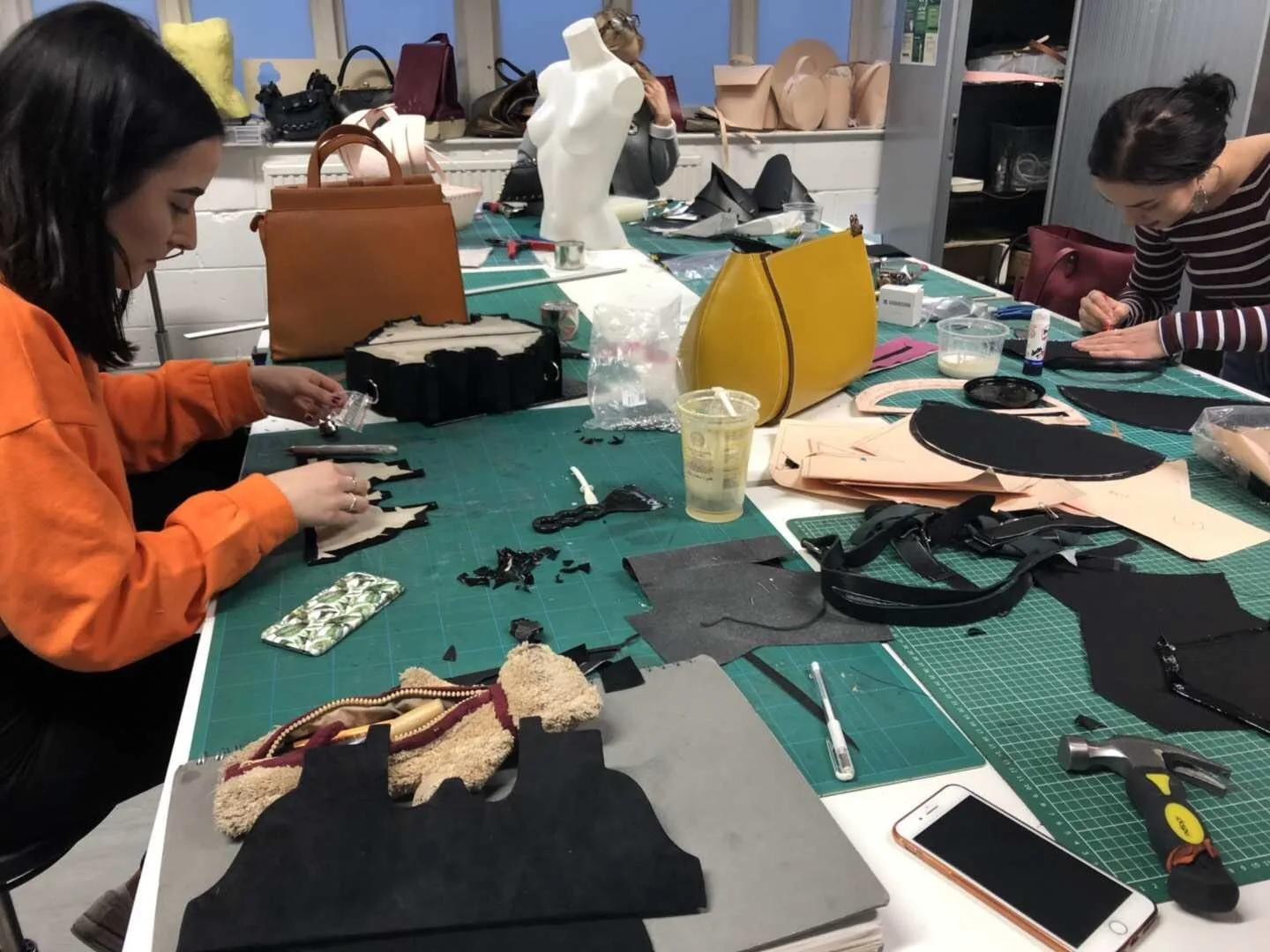 Sample makers cutting and checking garment pattern components at a development table