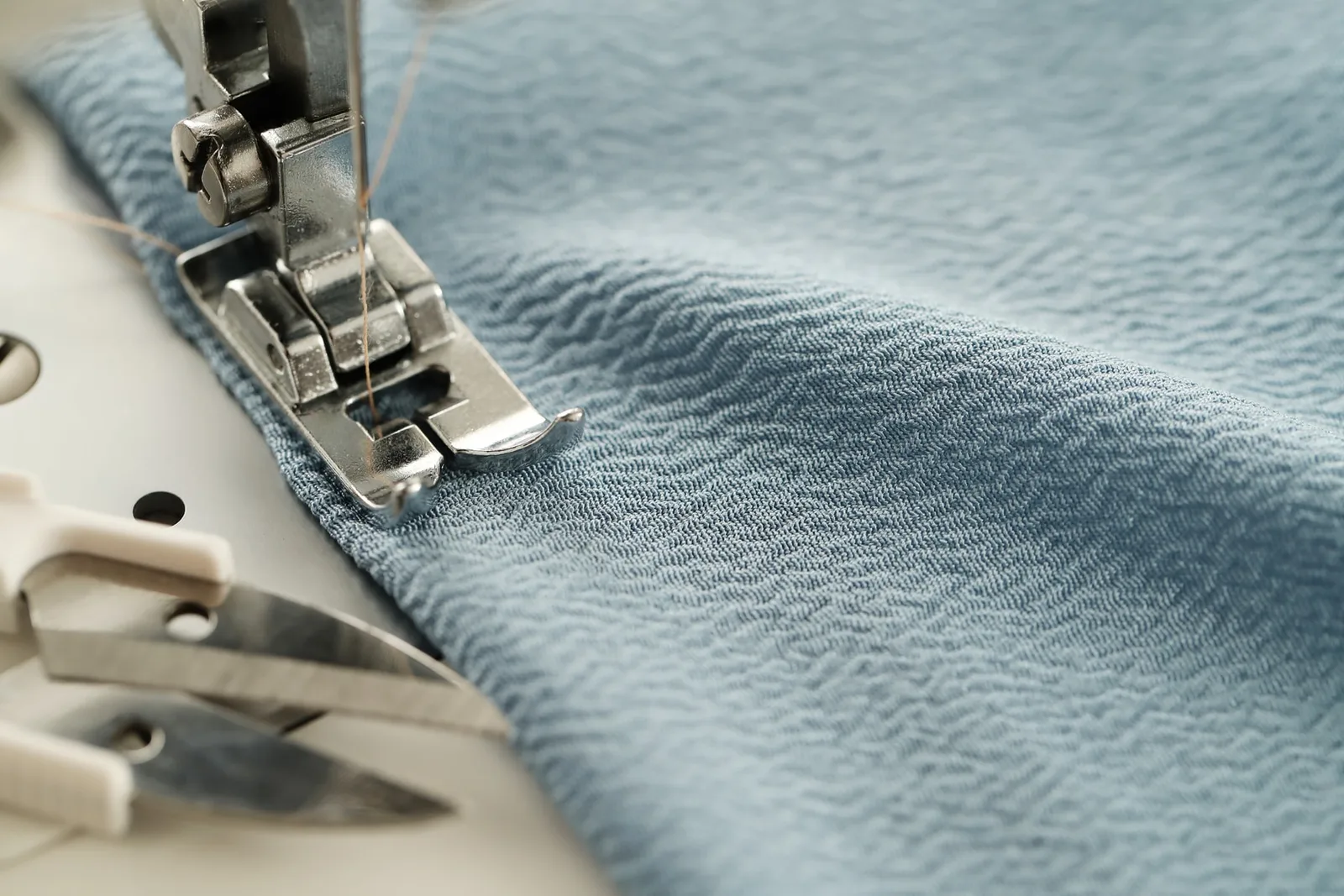 Close view of a sewing-machine presser foot and stitched fabric edge, showing seam and surface details to review during finishing
