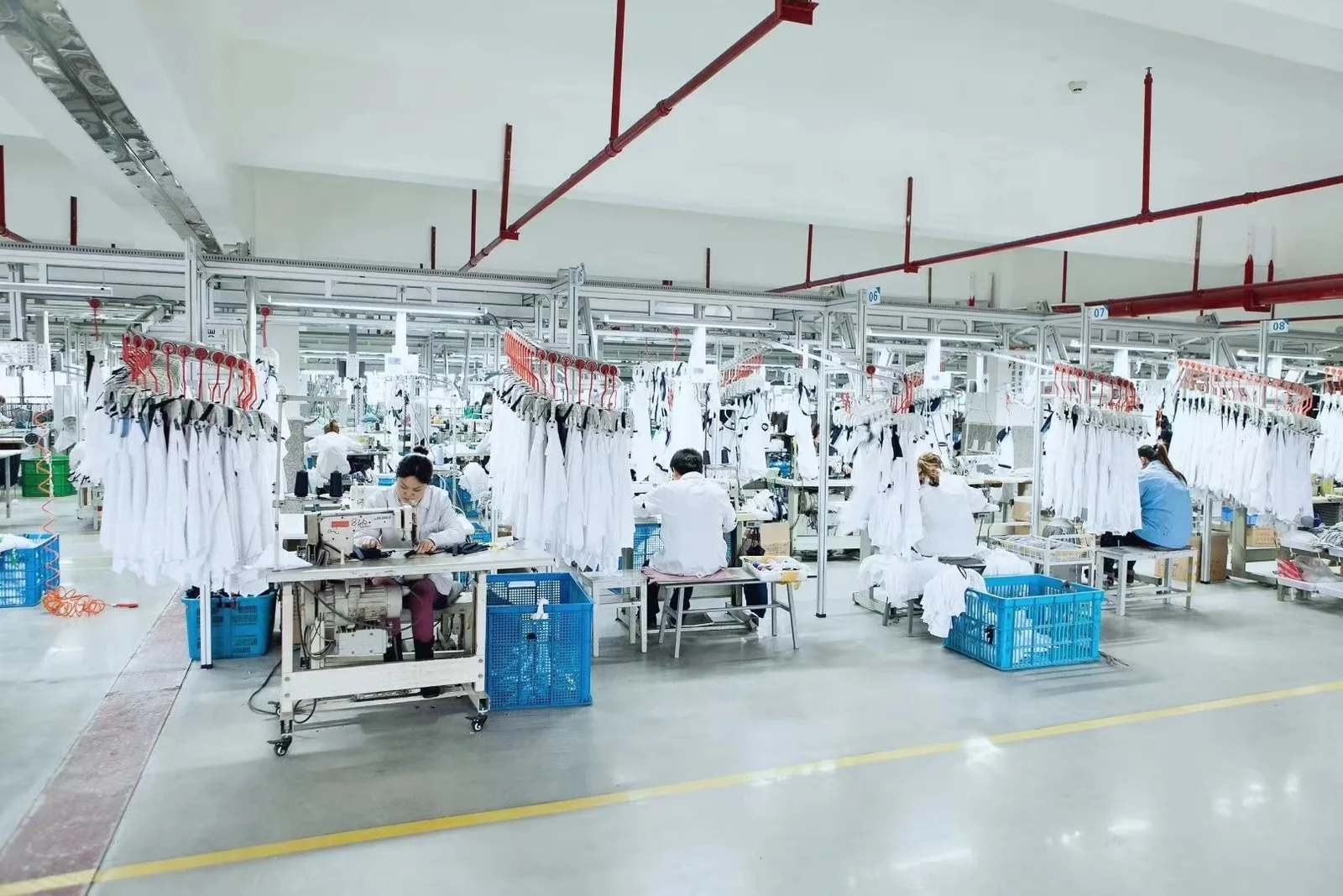 A garment workshop with suspended handling rails and organised workstations, illustrating line layout and work-in-progress controls