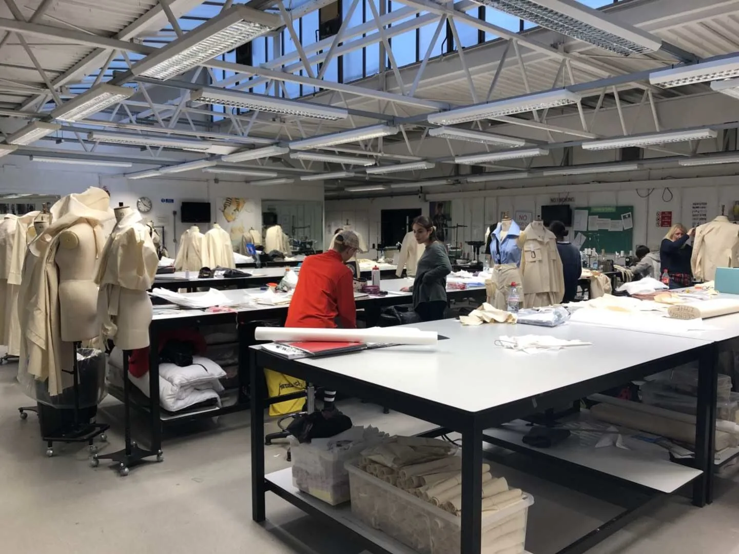 Apparel sample workroom with garment rails, dress forms and large development tables