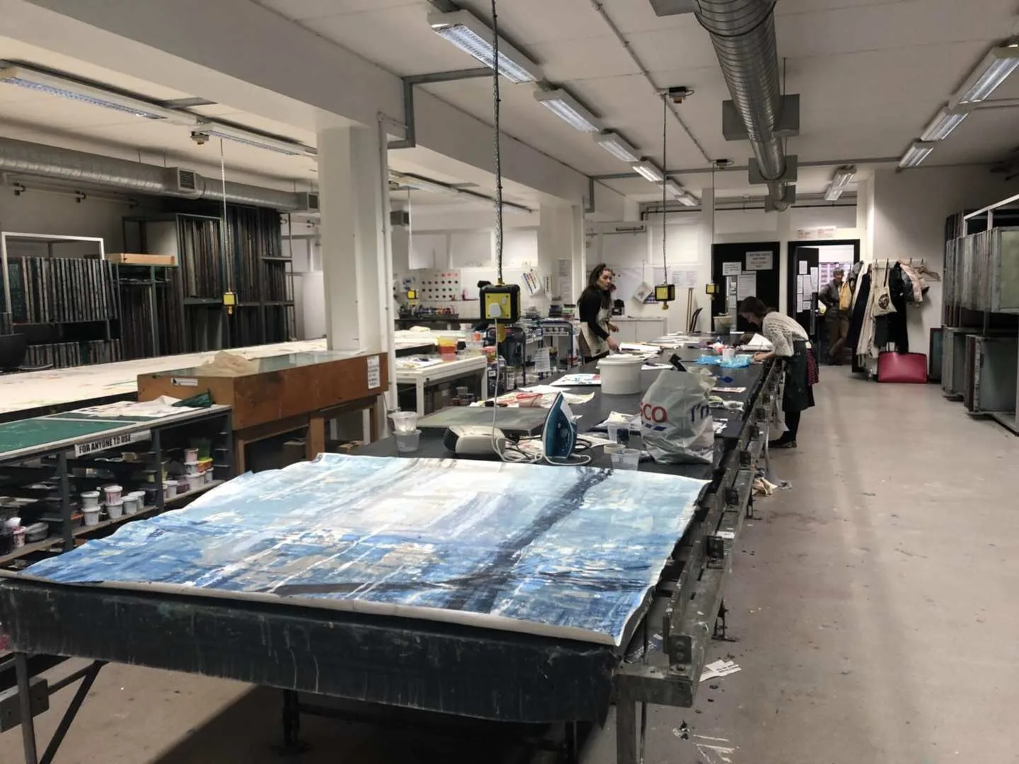 Fabric and garment-development tables in a sample studio used to organise a custom apparel range